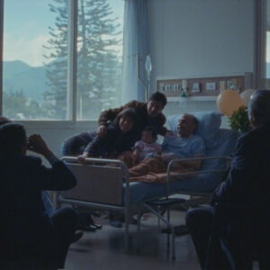 A group of people taking a picture with a man in a bed.