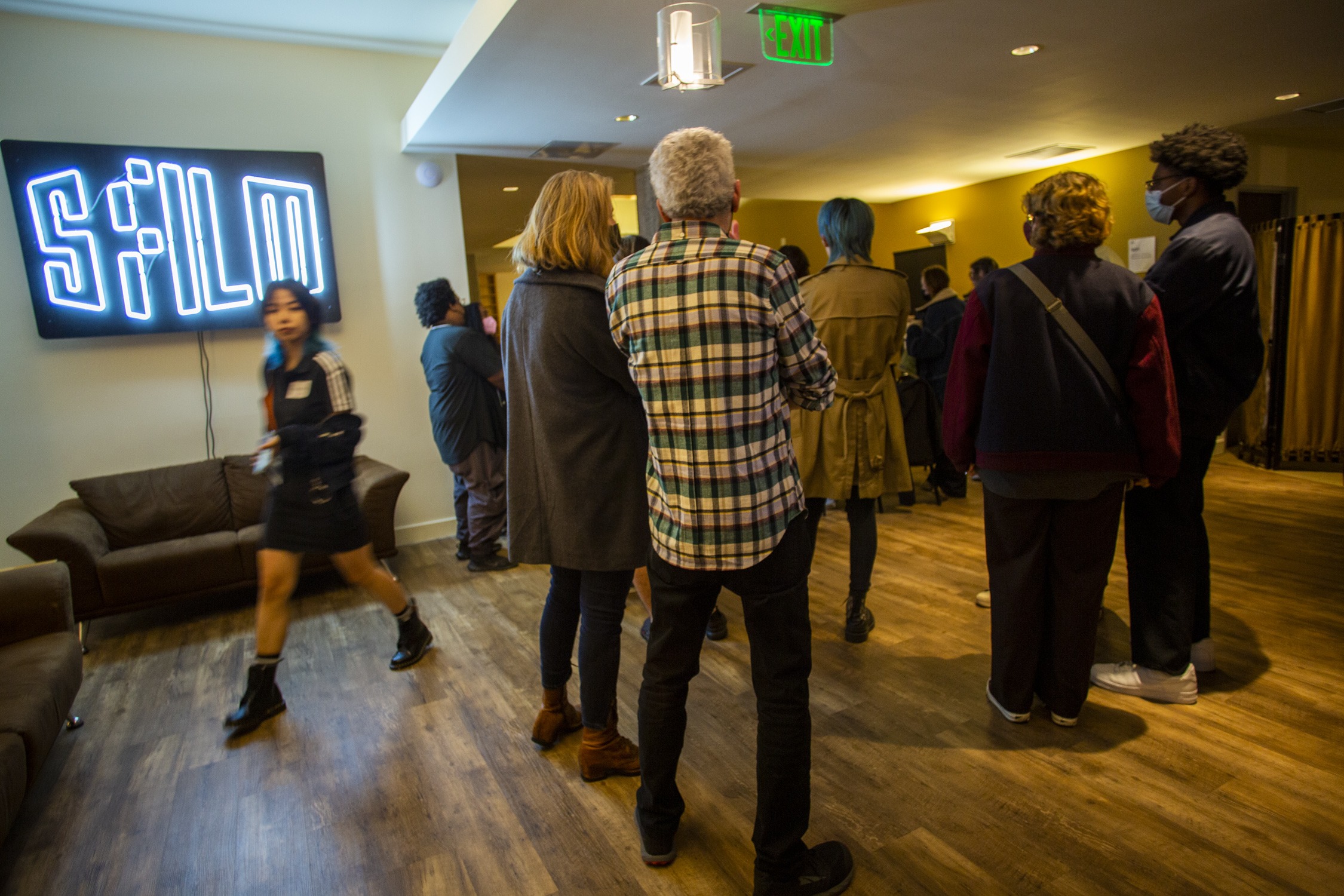 a woman passing by a group of people in front of sign that reads "SFFILM".