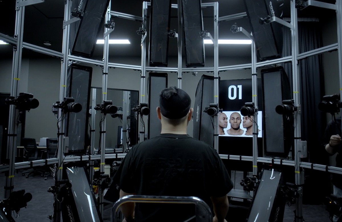 A man is sitting in a room with several monitors.