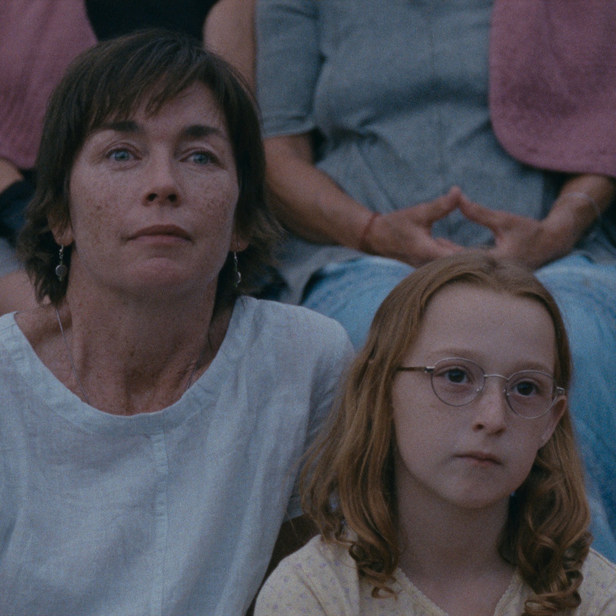 A woman and a girl sitting on a bench.