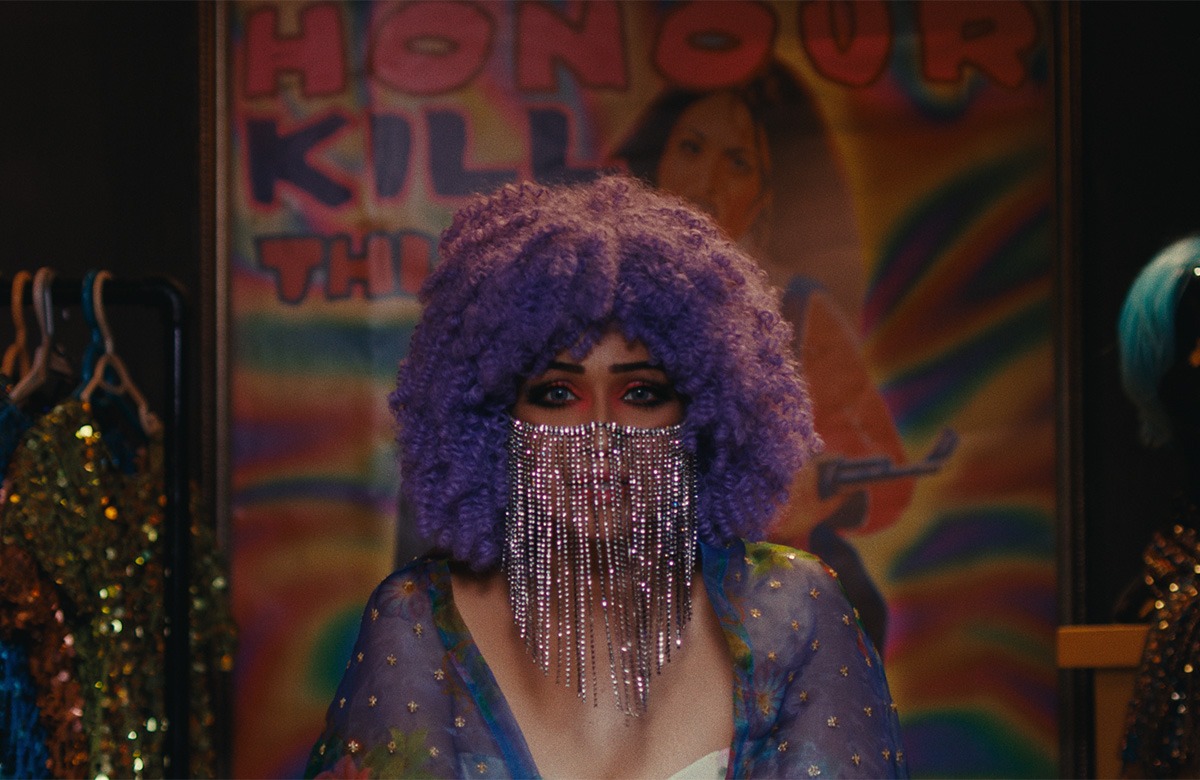A woman with a purple wig in front of a store.