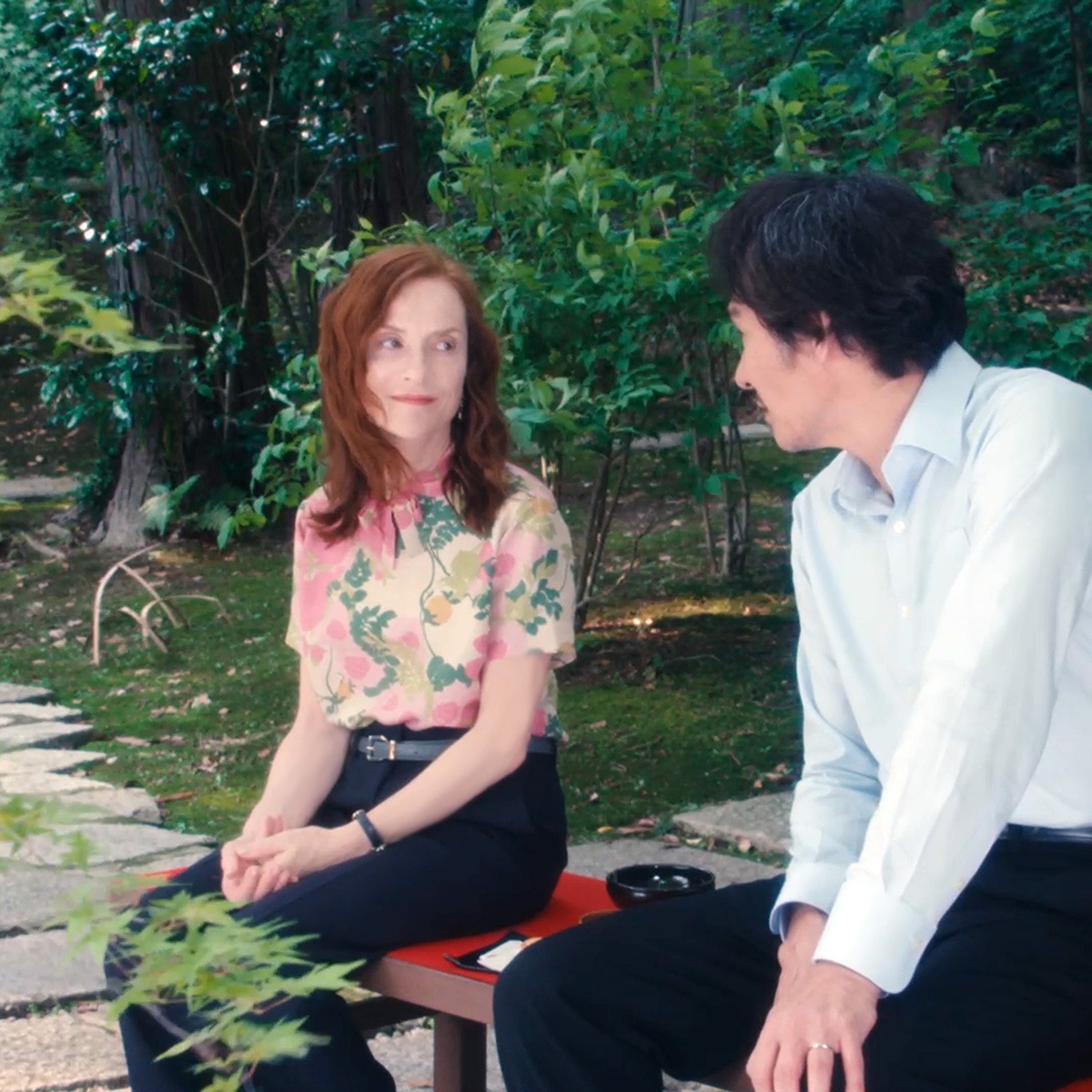 A woman and man sitting outside on a bench.